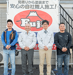 店舗看板の前に並ぶ従業員